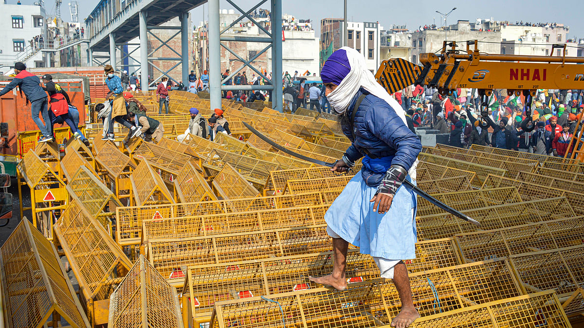 A farmer walks over the police barricades set up on a road at Akshardham to stop farmers during their during the Kisan Gantantra Parade amid the 72nd Republic Day celebrations.