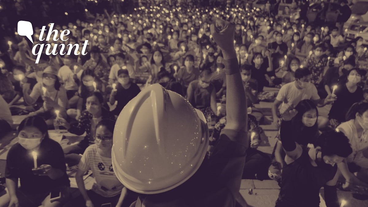 An anti-coup protestor raises his hand with clenched fist in front of a crowd during a candlelight night rally in Yangon, Myanmar on Sunday, 14 March.