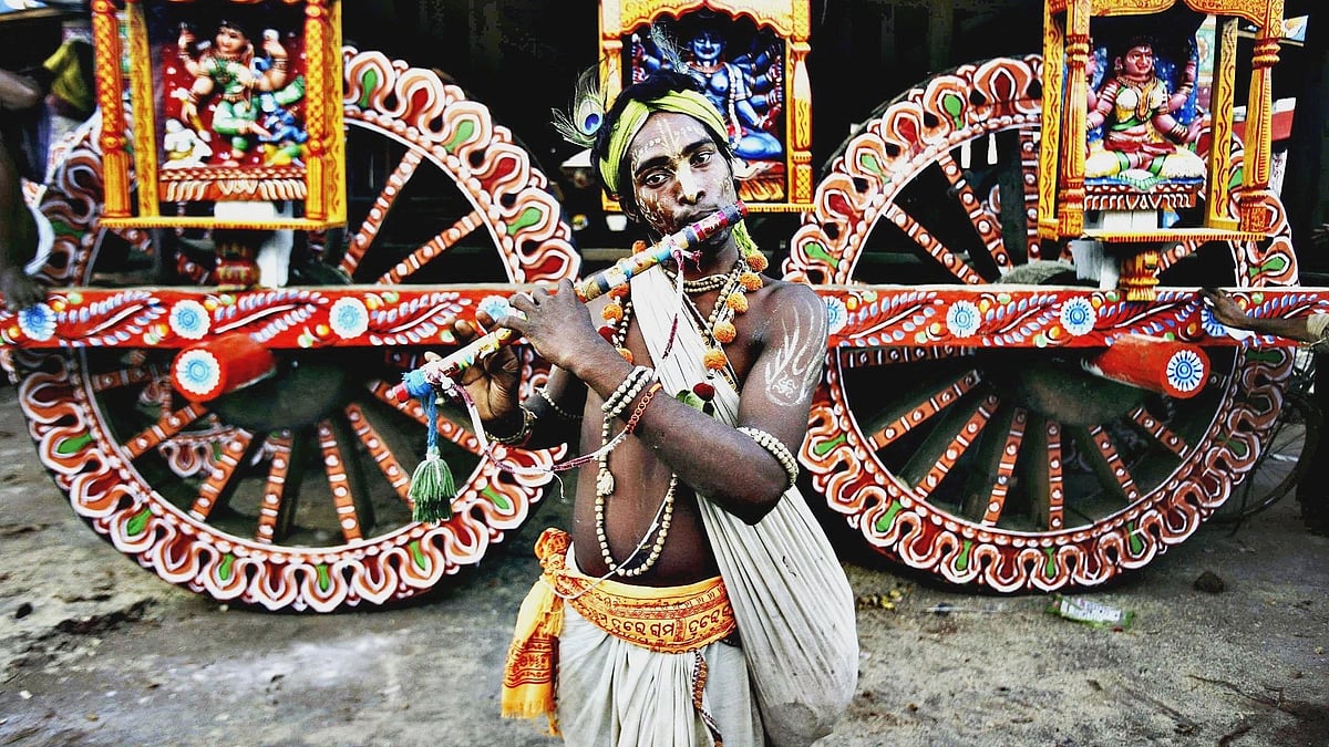 <div class="paragraphs"><p>A devotee in the attire of Lord Krishna poses for a photo near a chariot. </p></div>