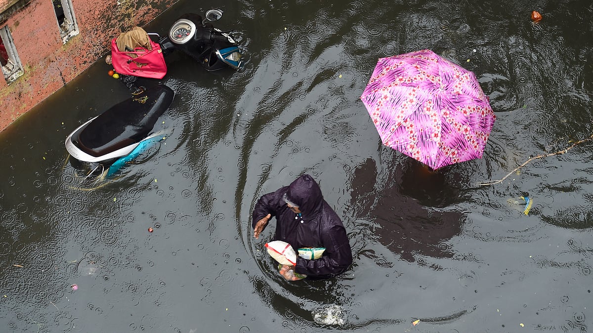 <div class="paragraphs"><p>People wade through a waterlogged street following heavy rain at KM Garden in Purasaiwakkam, in Chennai.</p></div>