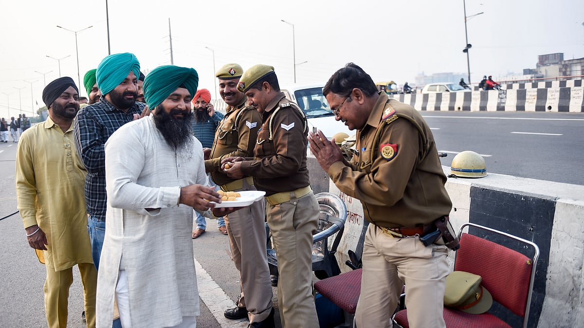 <div class="paragraphs"><p>Farmers offer sweets to police officers as they celebrate the culmination of their protest.</p></div>