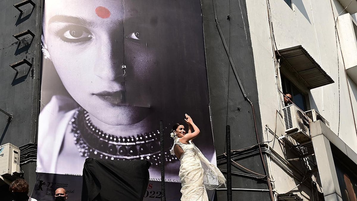 <div class="paragraphs"><p>Alia Bhatt in front of the poster for <em>Gangubai Kathiawadi.</em></p></div>