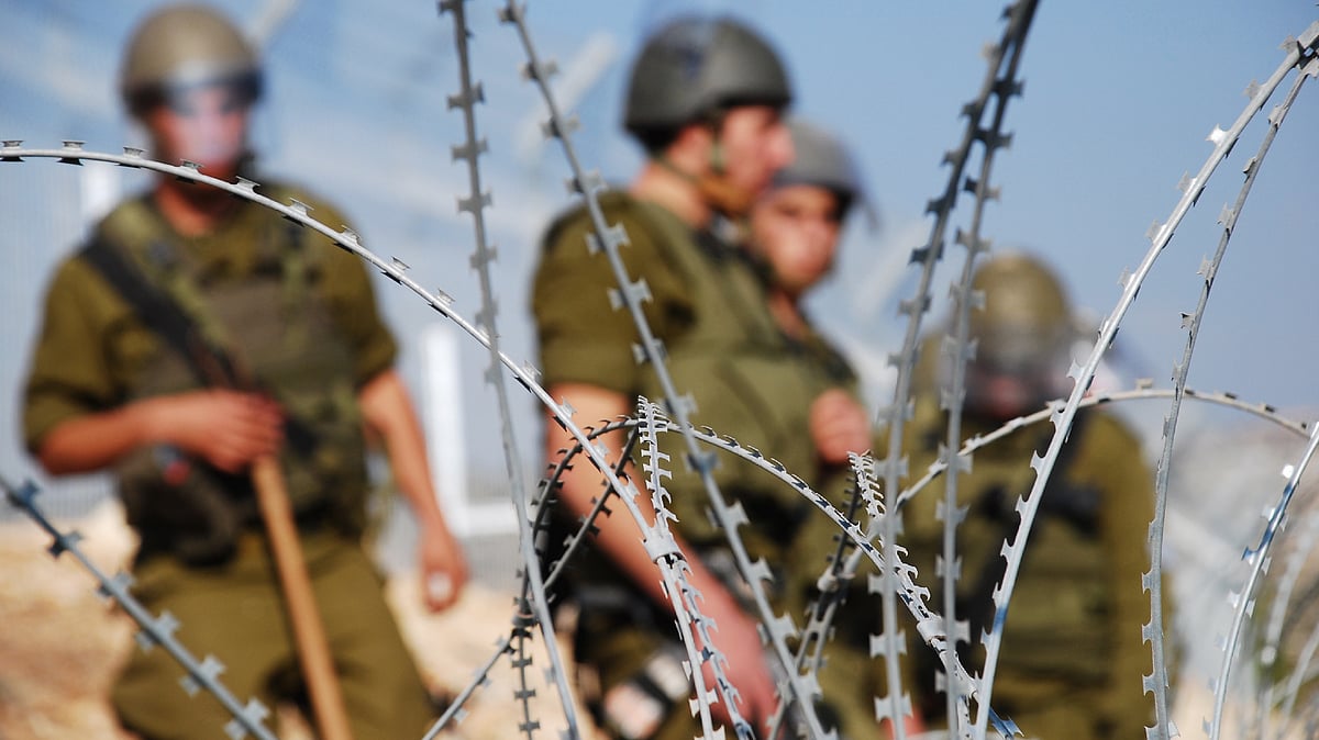<div class="paragraphs"><p>Four Israeli soldiers stand behind razor wire near a Palestinian village in the West Bank. Image used for representational purposes only. </p></div>