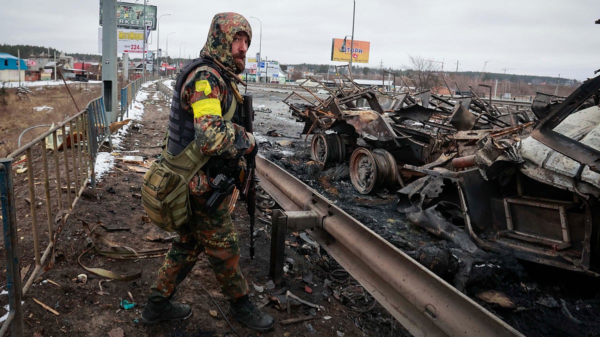 <div class="paragraphs"><p>An armed man stands by the remains of a Russian military vehicle in Bucha, close to the capital Kyiv, Ukraine. Representational image. </p></div>
