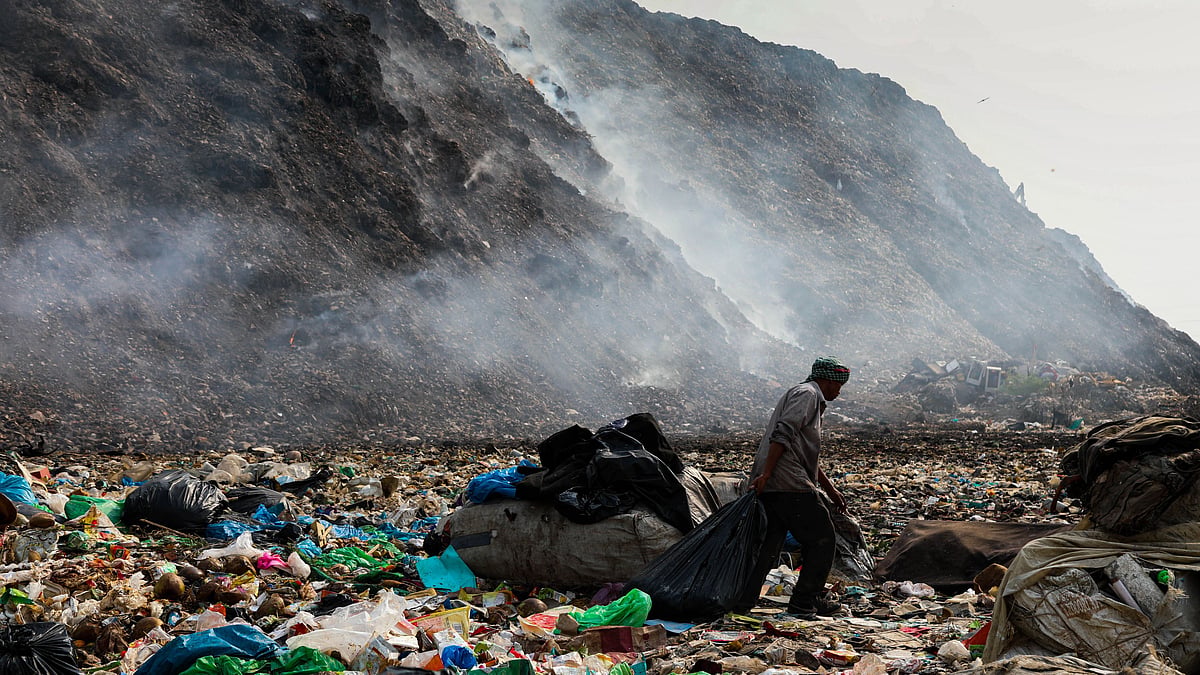 <div class="paragraphs"><p>A person picking waste in the background of a dumpsite fire in Delhi.</p></div>