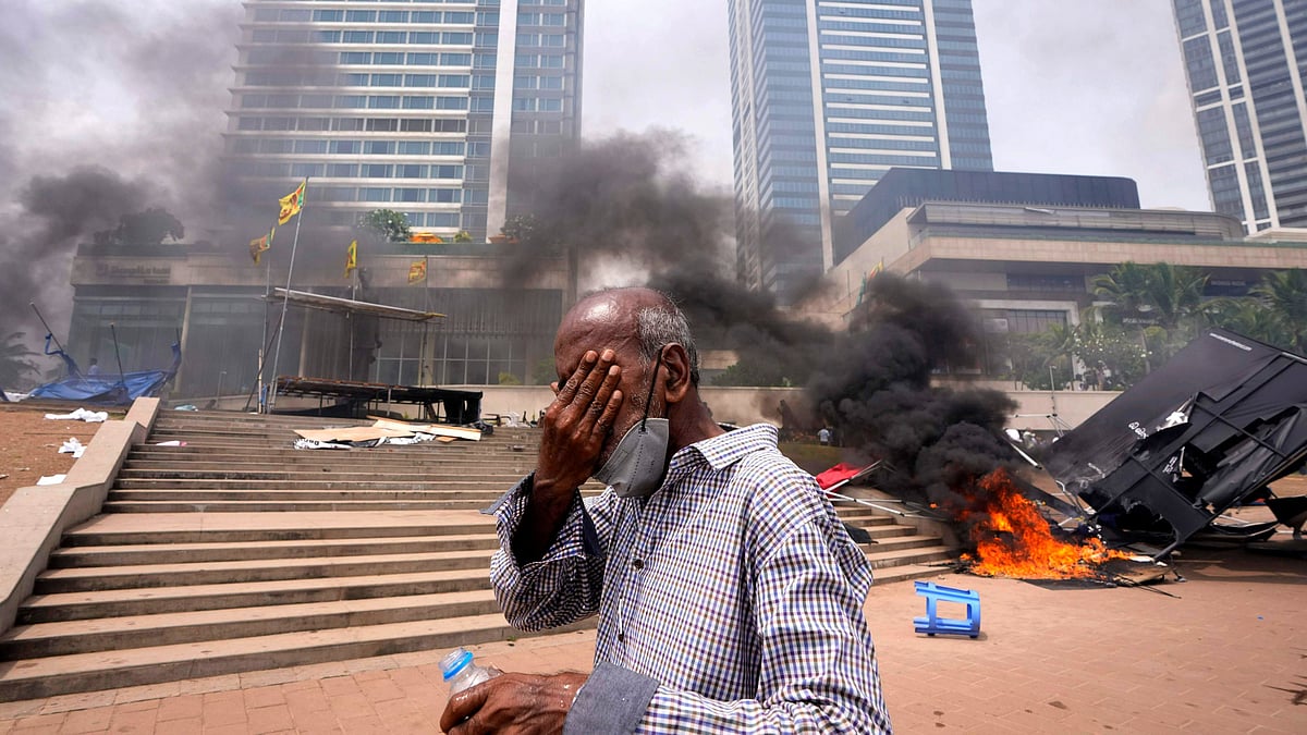 <div class="paragraphs"><p>A Sri Lankan man reacts to tear gas as he walks past the vandalised site of anti-government protests outside President Gotabaya Rajapaksa's office in Colombo on 9 May. </p></div>