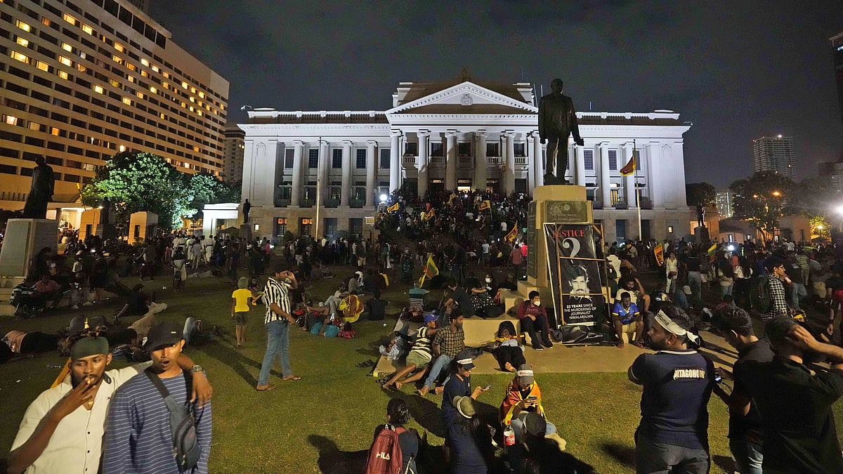 <div class="paragraphs"><p>Protesters sit and walk around the Sri Lankan President's office, in Colombo, Sri Lanka, on Saturday, 9 July.</p></div>