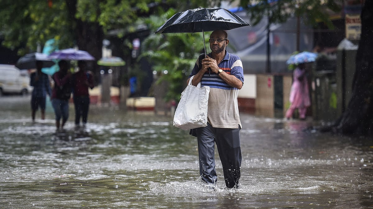<div class="paragraphs"><p>Mumbai: People holding umbrellas wade through a flooded road following heavy monsoon rains, in Mumbai, Tuesday.</p></div>