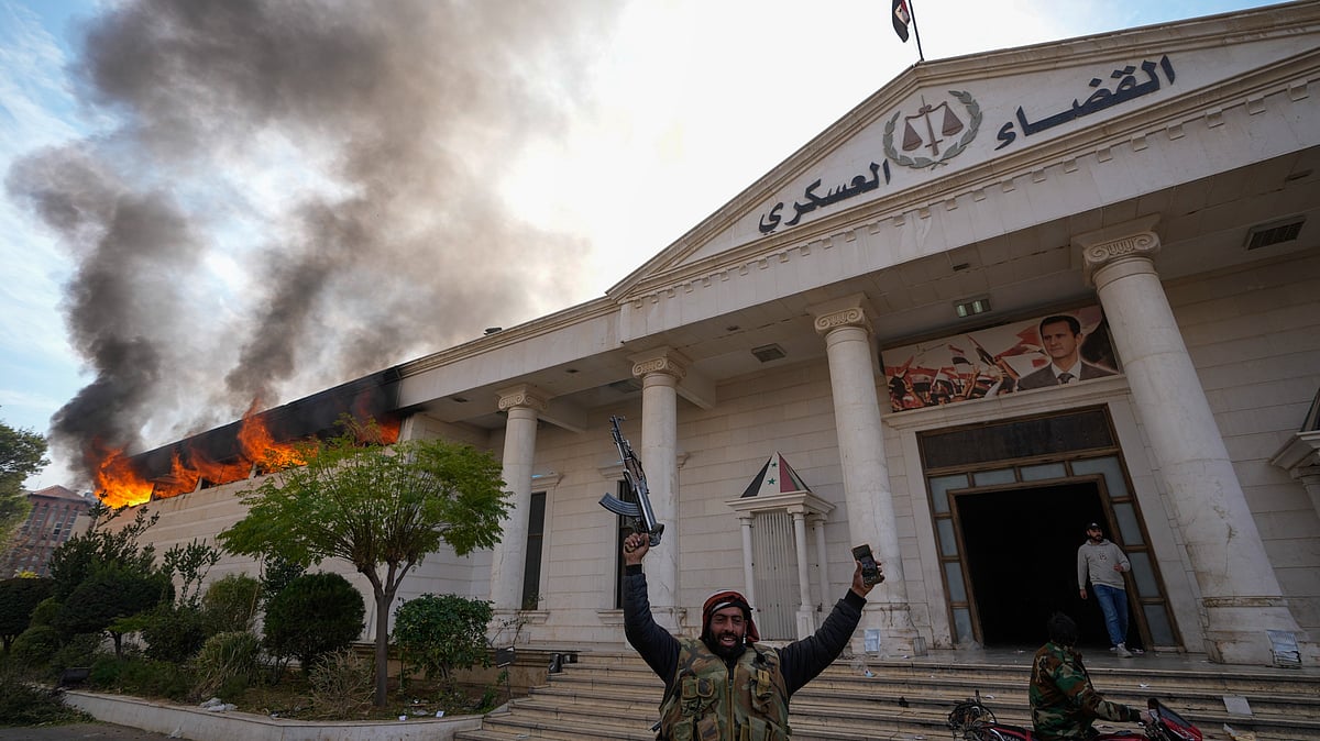 <div class="paragraphs"><p>Opposition fighters celebrate as they burn down a military court in Damascus, Syria on Sunday, 8 December. </p></div>