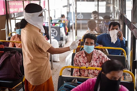 An APSRTC worker conducts thermal screening of a passenger at Pandit Nehru Bus Station in Vijayawada in May 2020