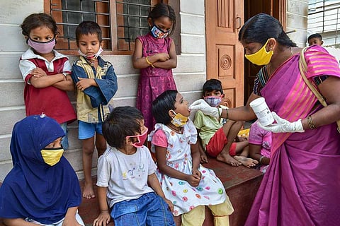 An ASHA worker distributing tablets to kids 