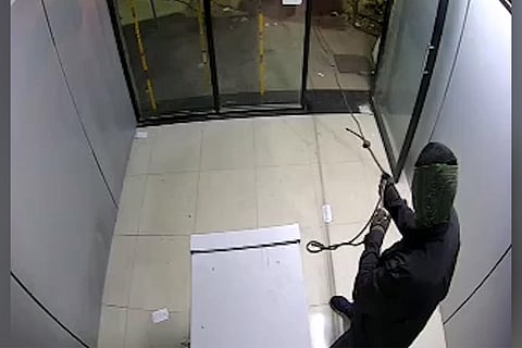 A man tying a rope around an ATM machine 