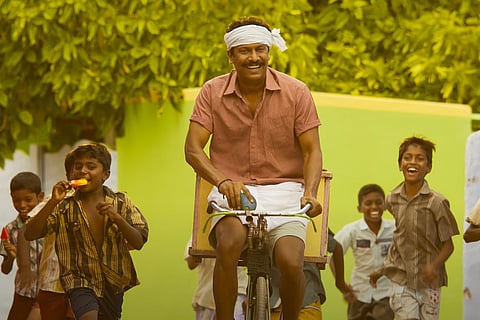Samuthikarini in a veshti riding a cycle with kids in the background 