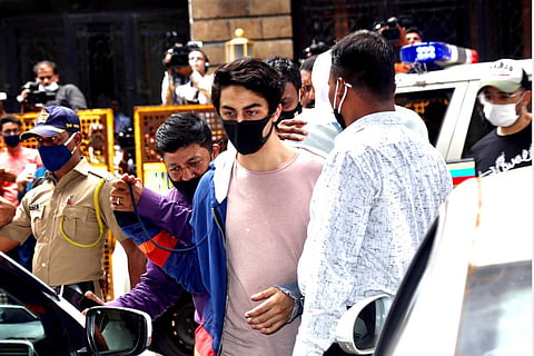 Aryan Khan wearing a pink T-shirt being escorted by NCB officials