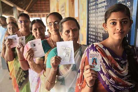 Women standing in line to vote, and holding up their Voter IDs