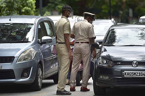 Two policemen walking on a street amid traffic
