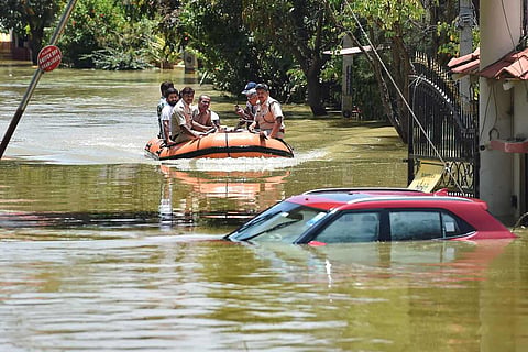 People riding on emergency rafts amid submerged vehicles in Bengaluru