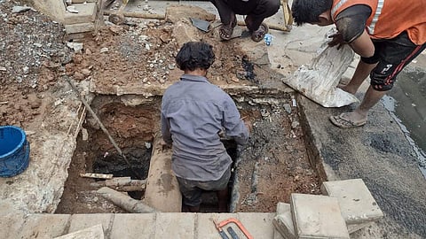 Worker enters a manhole to clean sewage