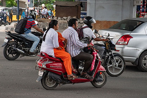 Two people seen on a two wheeler with a small child seated between them