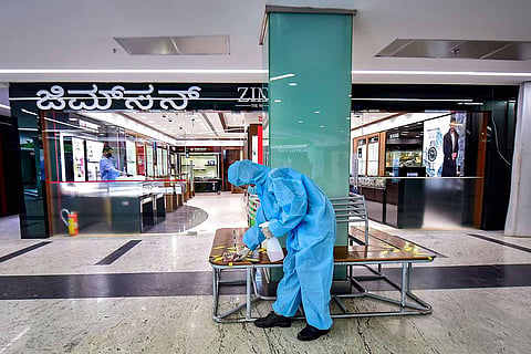 A PPE wearing man opening a store in Bengaluru