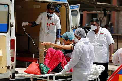 Health workers helping a patient into an ambulance