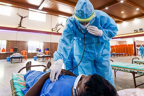 Doctor in PPE kit checking patient 