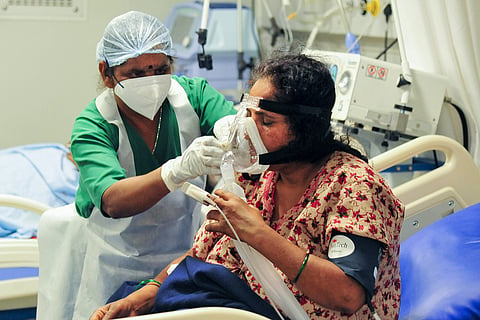 A health worker checks a COVID-19 patient on oxygen support at a hospital