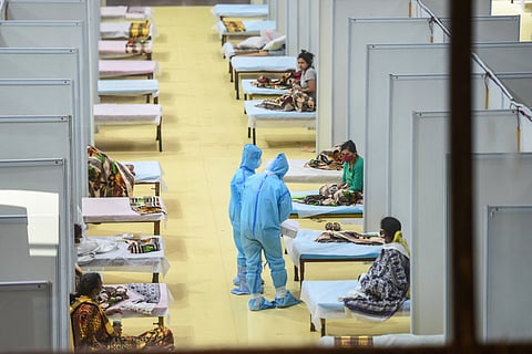 Two health workers in PPE talking to patients in a COVID-19 ward