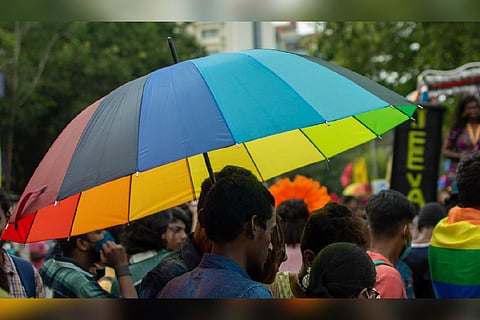 A person holding a rainbow-colored umbrella in Chennai Pride march
