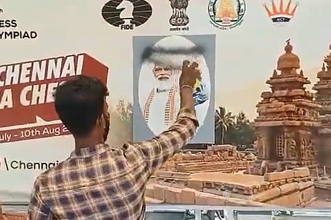 Man spraying PM's picture with black paint 