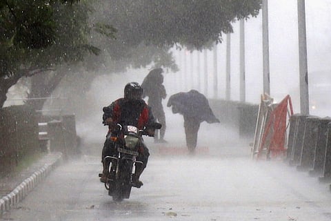 A man rides a bike in heavy rain near Marina Beach, Chennai