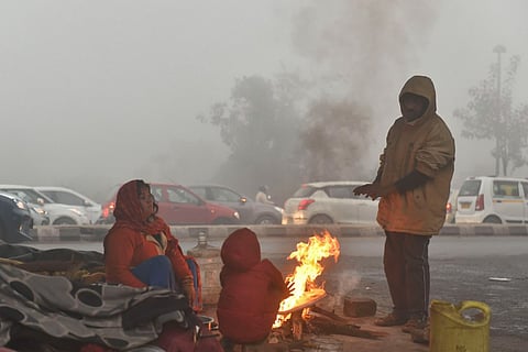 A group of people gathered around a bonfire to keep warm in winter