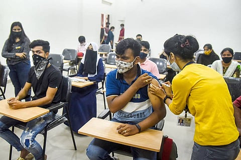 Health workers administering vaccine to college students 