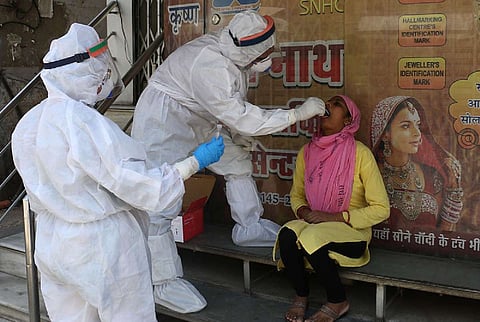 A woman at a bus stop having sample collected for COVID19 test 