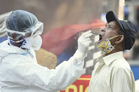 A health worker in a PPE suit collecting nasal swab sample from a mam for coronavirus test