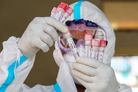 Healthcare professional wearing PPE suit and gloves checking samples 