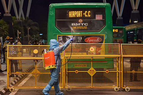 A man in PPE suit is sanitising a bus in Bengaluru which stands on the other side of a barricade