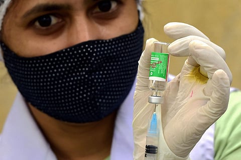 A woman holding up Serum Institute of India's Covishield Vaccine