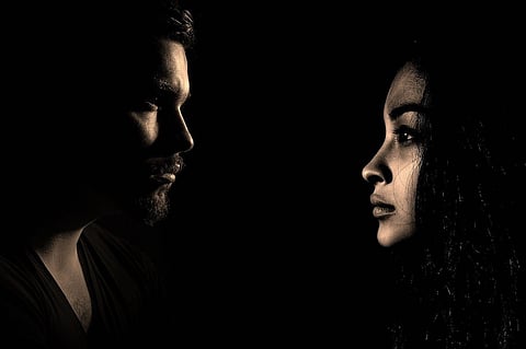 A man and woman face each other, image in low-light