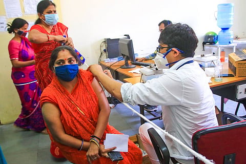 A health worker administers a COVID-19 vaccine dose to a woman
