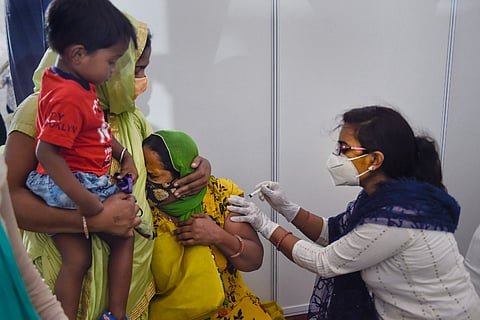 A woman being administered the vaccine by a female healthcare worker