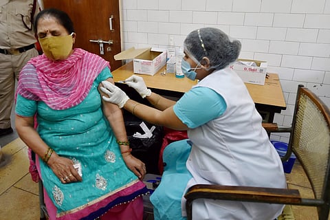 A woman receiving COVID-19 vaccine from a health worker