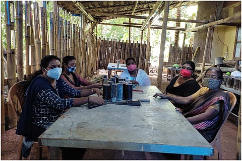 A group of women from Kerala bamboo craft enterprise Fibrent sitting around a table at work