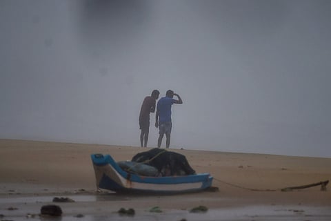Two men shield themselves from the heavy rain and the wind at a beach