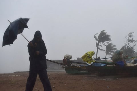 Silhouette of a man trying to hold an umbrella at a beach in heavy wind and rain