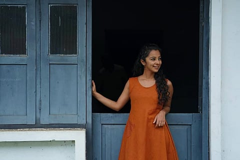 Darshana Rajendran is seen donning an tangerine dress in the image.