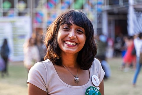 Bengaluru climate activist Disha Ravi in a white t-shirt smiling at the camera