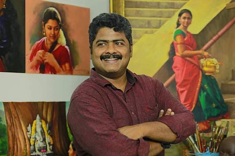 Elayaraja posing in front of his paintings 