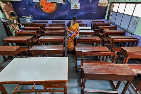 Staffers clean an empty classroom 