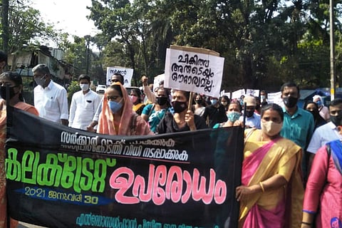 Group of people holding up banners and posters in Malayalam and protesting